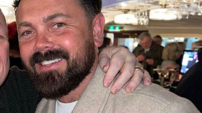 Ray Quinn, who has dark hair swept back and a dark beard and wears a beige woollen jacket.