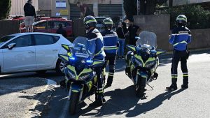Three French police officers in uniform arrive at Lakanal school on motorbikes.