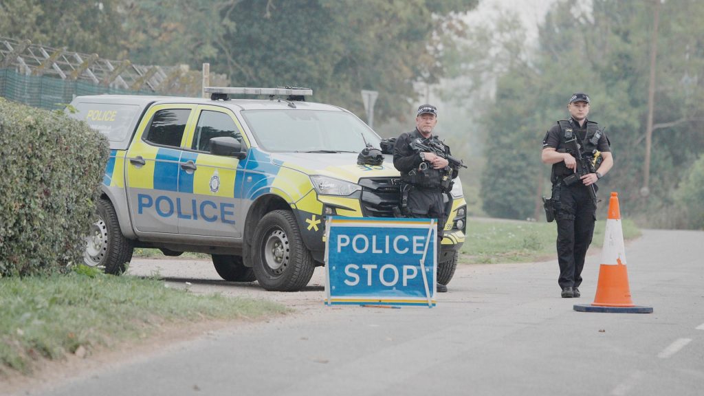 Police stand near a stop sign and a police vehicle near RAF Fairford