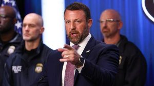 Markwayne Mullin speaking at a lectern and pointing, while some police officers stand behind him.