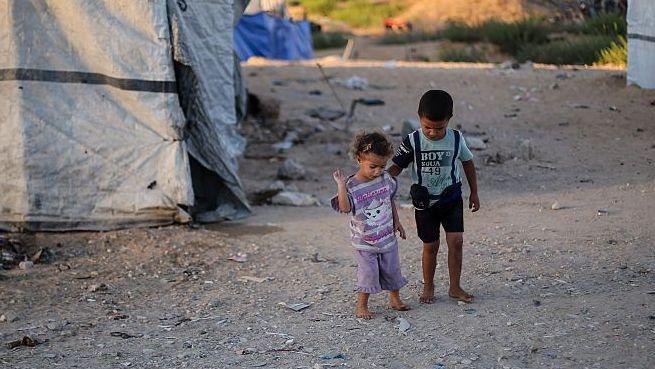 Two children stand beside tents on October 7, 2026 in Gaza City, Gaza